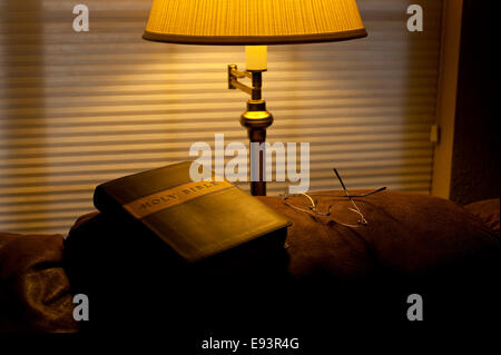 Bible sur l'arrière de la table avec la lumière solaire et la lumière chaude de la lampe avec rosaire Banque D'Images