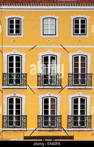 Bâtiment traditionnel avec une façade jaune et de grandes fenêtres avec balconets à Lisbonne, Portugal. Banque D'Images