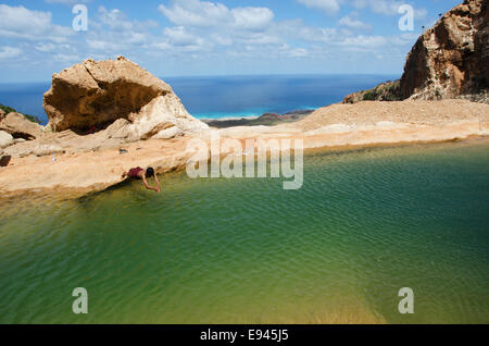 Socotra, Homhil Plateau, Yémen : un garçon de plonger dans l'oued, une piscine d'eau douce naturelle, qui aperçu de la mer d'Oman Banque D'Images