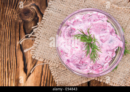 Salade de harengs rose dans un bol (avec de la betterave et des herbes fraîches) sur fond de bois Banque D'Images
