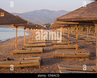 Tôt le matin sur la plage par Doryssa Bay Resort Hôtel à Pythagorion Samos Grèce, Lumière dorée et vide en attente de chaises longues Banque D'Images