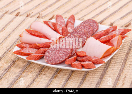 Saucisses fraîches dans la plaque sur fond de nattes de bambou. Banque D'Images