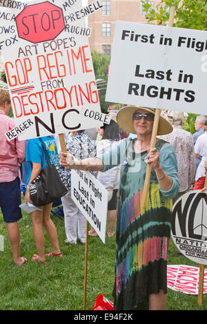 Asheville, Caroline du Nord, USA - 4 août 2014 : un manifestant lundi morale détient plusieurs signes de protestation politique GOP NC Banque D'Images