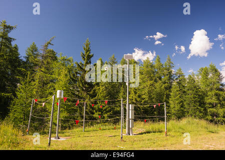 Station météo à haute altitude sur les Alpes italiennes avec forêt de mélèzes vert et bleu ciel. Banque D'Images