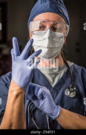 Les femmes concernées Médecin ou Infirmière mise sur le visage de protection Porter des gants chirurgicaux et. Banque D'Images