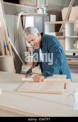 Heureux carpenter couper du bois avec petite scie Banque D'Images