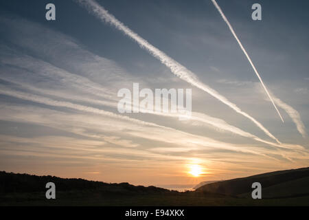 Des traînées de vapeur chimique,plans,sentiers, sunrise Mwnt,West Wales Banque D'Images