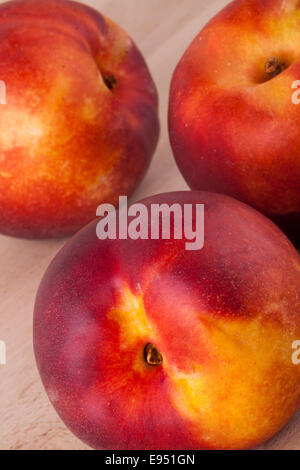 Trois frais mûrs savoureux nectarines juteuses sur des planches de bois peint en blanc pour une collation saine et l'alimentation Banque D'Images