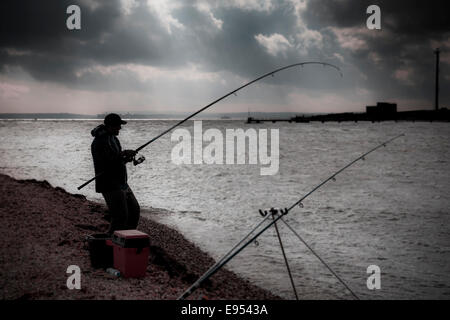 Plage semi silhouette de pêcheur avec flexion de la tige à partir de choc dans ses prises. Banque D'Images