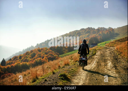 Scène d'automne avec une moto sur une route de terre à l'heure d'or Banque D'Images