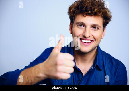 Happy man giving Thumbs up sign on blue background Banque D'Images