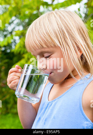 Cute little girl drinking water outdoors Banque D'Images