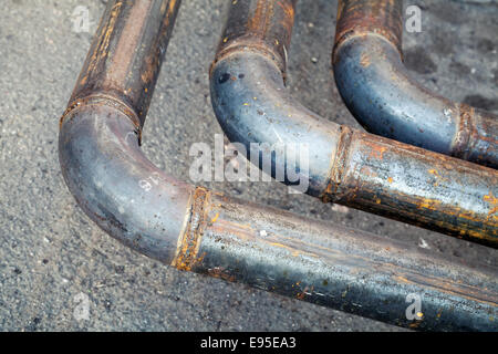 Coude de plein air industriel pipeline en acier sur l'asphalte de la route en milieu urbain Banque D'Images