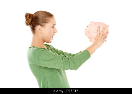 Jeune femme choquée face à Pink Piggy Bank Banque D'Images