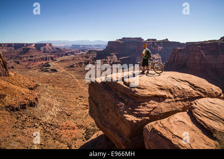 Whit Richardson stand avec son vtt sur le Canyon surplombant Shafer Rim Trail blanc, le Parc National de Canyonlands, Moab, Banque D'Images