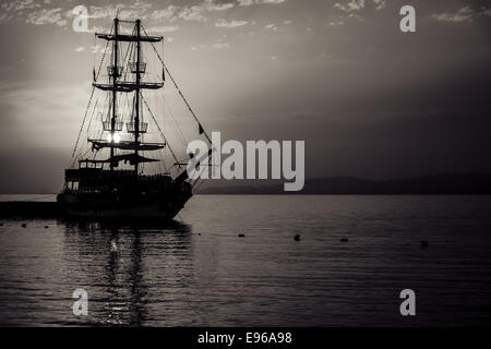Coucher de soleil sur la mer et un voilier dans la baie. Stylisation. Tonifiant. Sépia. Banque D'Images