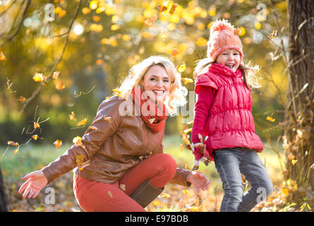 Parent heureux et jeux de plein air pour enfants avec des feuilles jaunes d'automne Banque D'Images