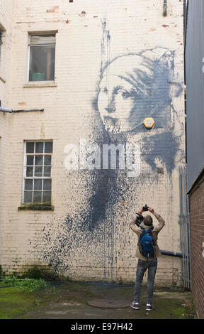 Bristol, Royaume-Uni. 21 Oct, 2014. La dernière fresque Bansky fille avec le tympan percé a paru récemment, c'est une parodie de Vermeer Girl with a Pearl Earring, les bijoux d'être remplacées par un système d'alarme. Au cours des 24 dernières heures, il a été saccagé par les éclaboussures de peinture sur elle. Crédit : Mr Standfast/Alamy Live News Banque D'Images