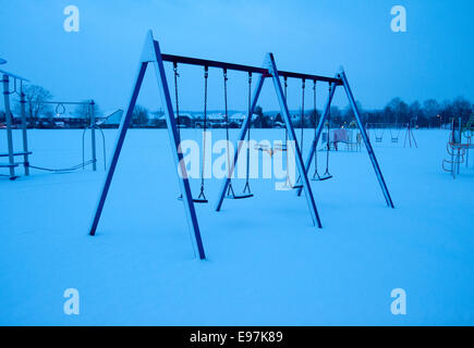 La neige a couvert des balançoires dans un parc couvert de neige et désert Banque D'Images