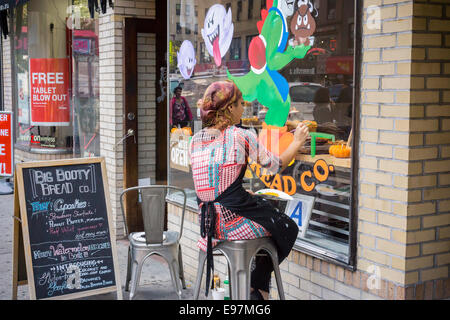 Un peintre d'enseignes ornent la fenêtre du Big Booty bakery Bread Co. à Chelsea à New York Banque D'Images