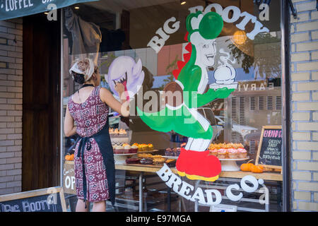 Un peintre d'enseignes ornent la fenêtre du Big Booty bakery Bread Co. à Chelsea à New York Banque D'Images