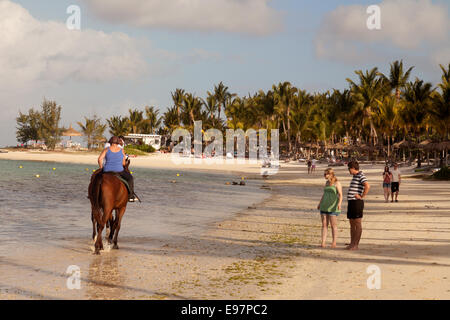 Les gens de l'équitation sur la plage au coucher du soleil, Plage de Belle Mare, Ile Maurice Banque D'Images