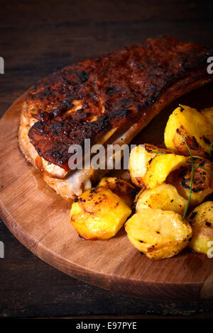 Pommes de terre au four et côte de boeuf dans la sauce barbecue sur fond de bois, selective focus Banque D'Images