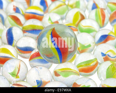 Un groupe de billes de verre avec une grande en haut sur une surface lumineux blanc. Banque D'Images