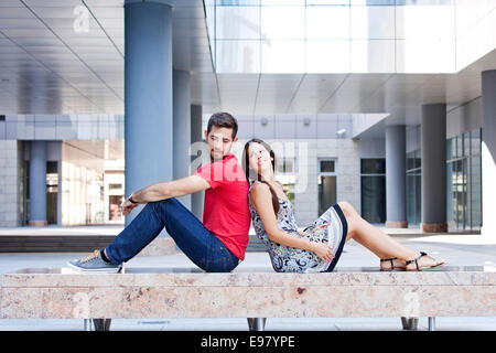 Happy young couple est assis dos à dos sur le campus Banque D'Images