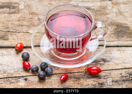 Tasse en verre de thé rouge karkade avec baies sauvages sur fond de bois Banque D'Images