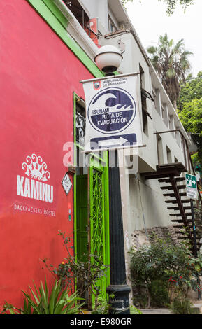 Panneau de route d'évacuation du tsunami à l'extérieur d'une auberge de routards dans la banlieue côtière de Barranco, Lima, Pérou Banque D'Images