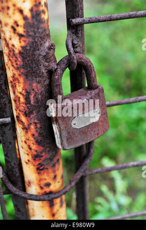 Un cadenas rouillé sur un portail en fer corrodées Banque D'Images