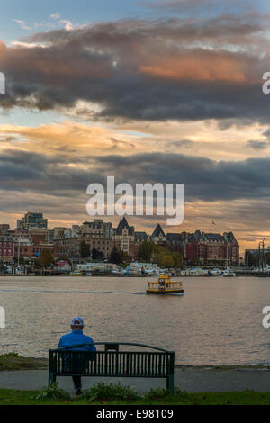 Man relaxing on bench en regardant Victoria ville vu de Walkway-Victoria Songhees, British Columbia, Canada. Banque D'Images