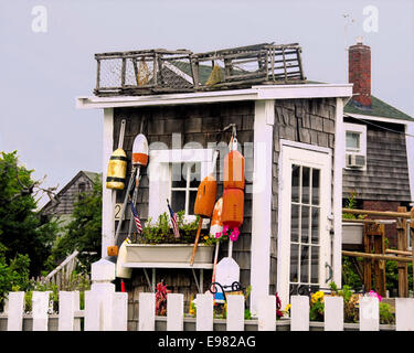 Un petit hangar décorativement composé dans la section des arts du Massachusetts Rockport Rockport lobster traps bouées de fleurs. Piquet blanc Banque D'Images