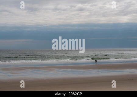 Seul figure sur une large vista beach surf océan ciel. La solitude l'auto réflexion sont thème. La lumière est les formations de nuages spirituels Banque D'Images