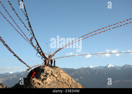 Moine tibétain qui met en place les drapeaux de prières près de monastère au-dessus de Leh, Ladakh, Inde. Banque D'Images