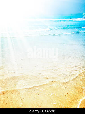 Soleil d'été lumineux sur une plage tropicale avec les rayons de soleil rayonnant à travers le bleu turquoise de l'eau et videz le sable Banque D'Images