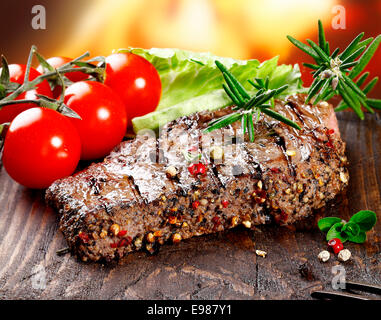 Un service d'offres succulentes grillades steak poivre garni de laitue, tomate et herbes de romarin frais Banque D'Images