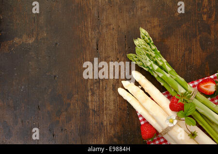 Les asperges et les fraises sur une planche en bois avec copyspace Banque D'Images