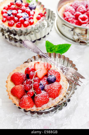 Fruits frais Gourmet mélange de baies tartelettes croustillantes sur les croûtes à tarte or servi dans des décors métalliques cannelés moules à tarte Banque D'Images