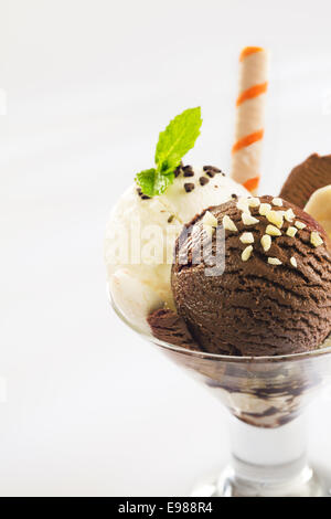 Boules de chocolat et glace vanille surmontée de noix hachées dans un verre conique plat parfait Banque D'Images