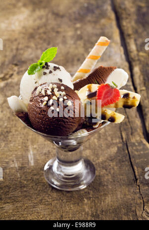 Boules de chocolat crémeux vanille et garni de glace à écrous sur une banane split mûrs dans un verre conique Banque D'Images