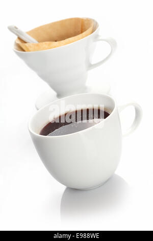 Tasse de café noir riche préparé avec un blanc portable chine filtre et filtre en papier utilisés pour produire des portions individuelles Banque D'Images