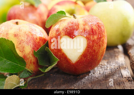 Fresh red apple sur une vieille table en bois vieilli texturé avec un coeur dentelle Banque D'Images