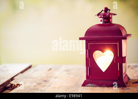 Rouge décoration lanterne en métal avec un coeur éclairé par une découpe glowing bougie avec copyspace de Saint Valentin ou de Noël Banque D'Images