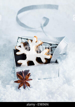 Noël encore la vie d'un flocon de neige de Noël cookie dans une boîte-cadeau en argent nichée dans la neige Banque D'Images