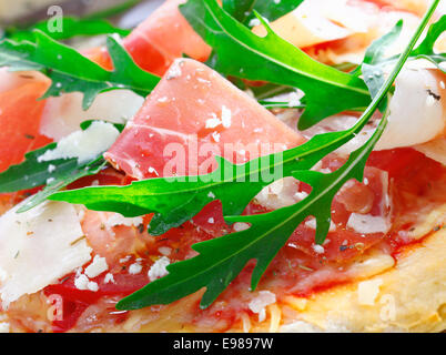 Libre de délicieux ingrédients frais utilisé comme garniture pour pizza italienne de fines tranches de jambon, tomates, herbes fraîches, fromage et roquette Banque D'Images