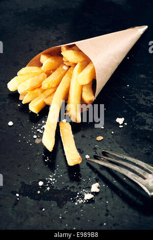 Sex salé pommes de terre rissolées dans un cornet de papier,et un tablier métallique close up Banque D'Images