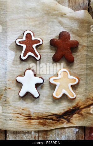 4 Gingerbread men avec un archet d'or sur un fond grunge pour Noël. Banque D'Images