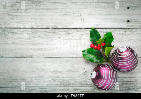 Houx de Noël et de jolies boules rouges avec une configuration en spirale sur blanc rustique en bois panneaux peints avec beaucoup de texture et de similibois copyspace Banque D'Images